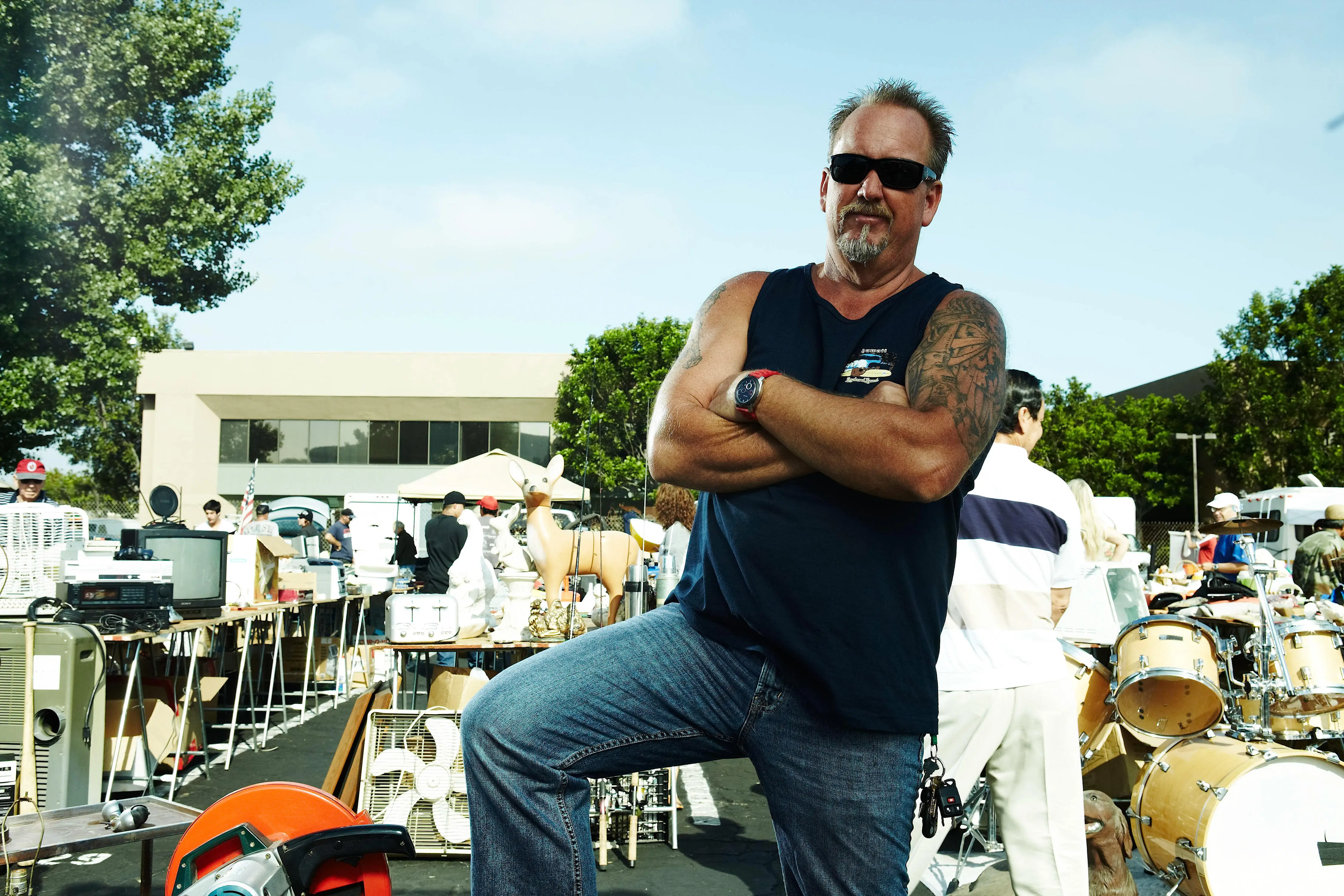 Darrell Sheets of Storage Wars season 2 standing with arms crossed at an outdoor sale.