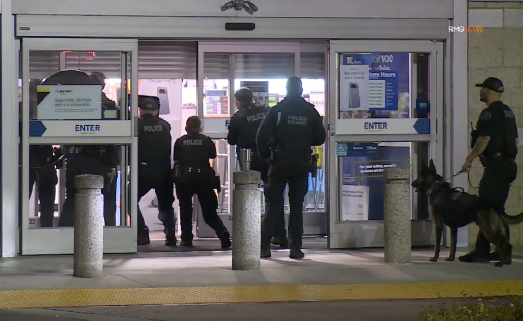 Police officers surrounding the entrance of a Best Buy store.
