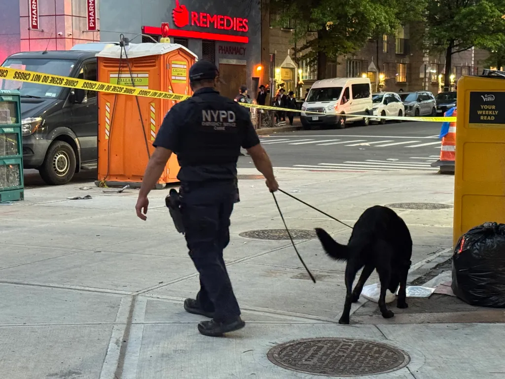 NYPD officer with a police dog at a crime scene.
