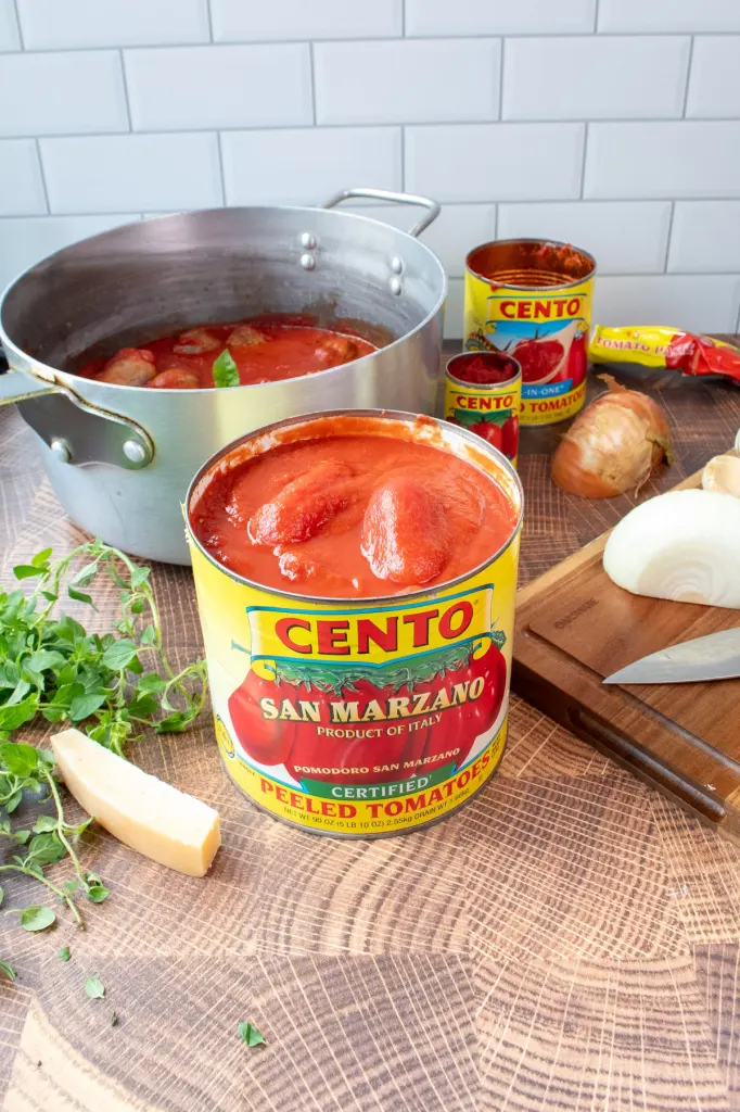 A can of Cento Certified San Marzano Peeled Tomatoes next to cooking ingredients.