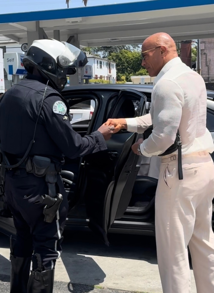 Dwayne Johnson shaking hands with a motorcycle police officer in Hollywood.