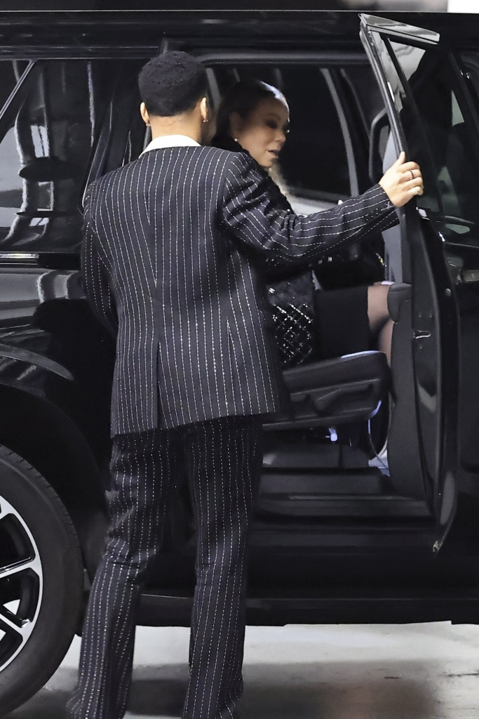 Mariah Carey and Anderson .Paak holding hands as they enter a black car.