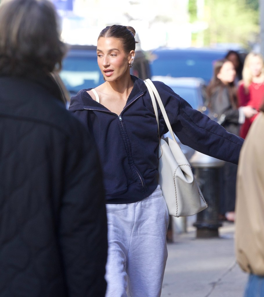 Amanda Batula walks down the street carrying a white handbag.