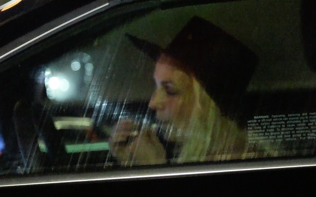 Britney Spears in a car, possibly driving, at night, with her face partially visible through the window.
