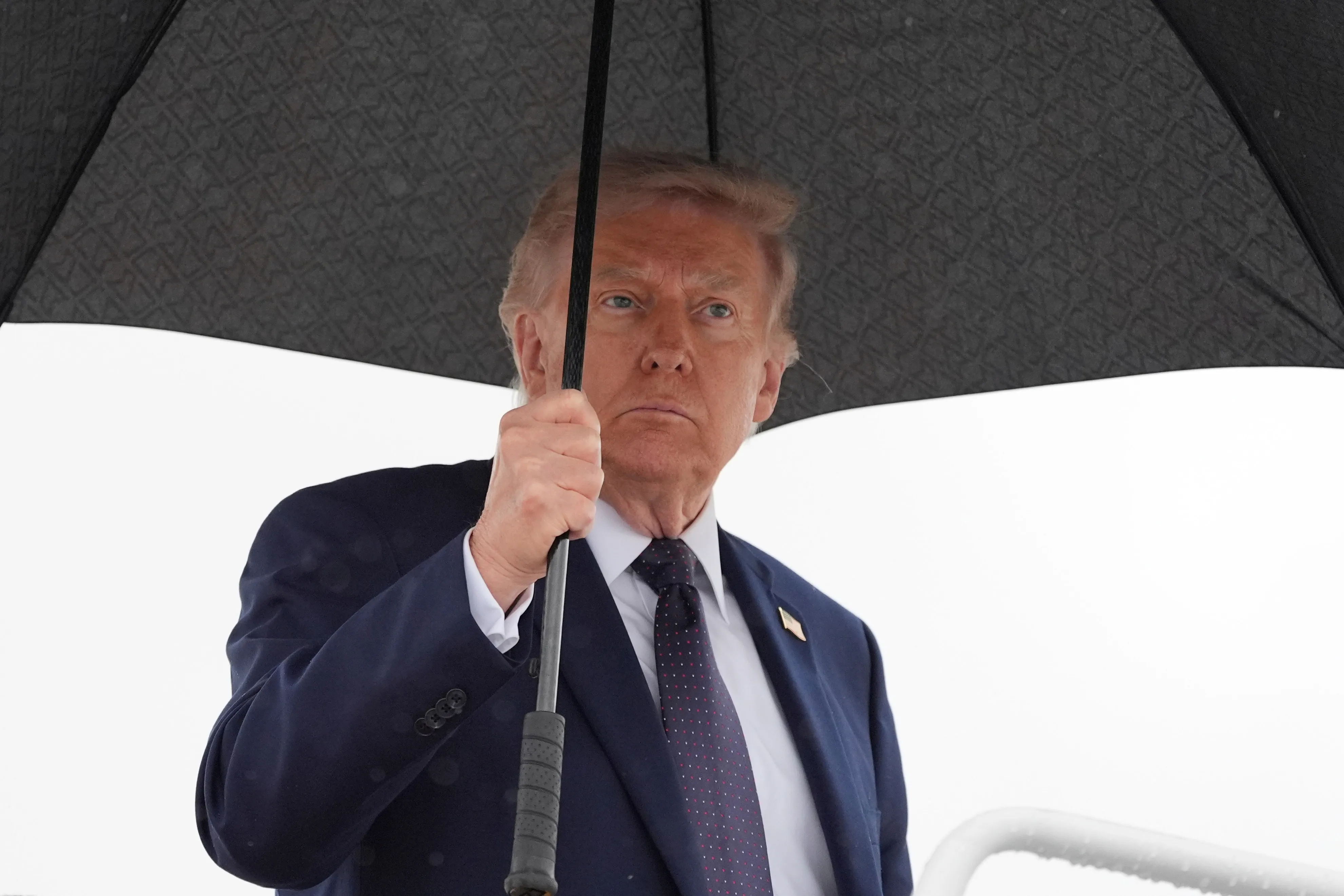 President Donald Trump holding an umbrella while boarding Air Force One.