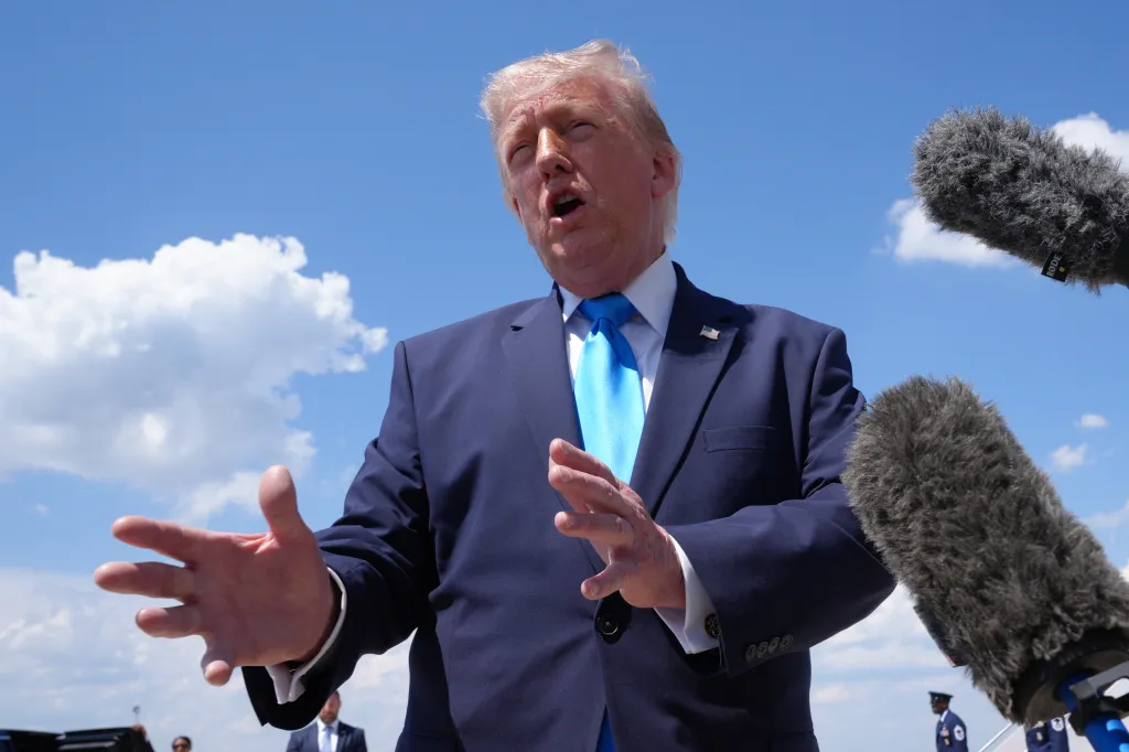 Donald Trump speaks into microphones while standing outdoors.