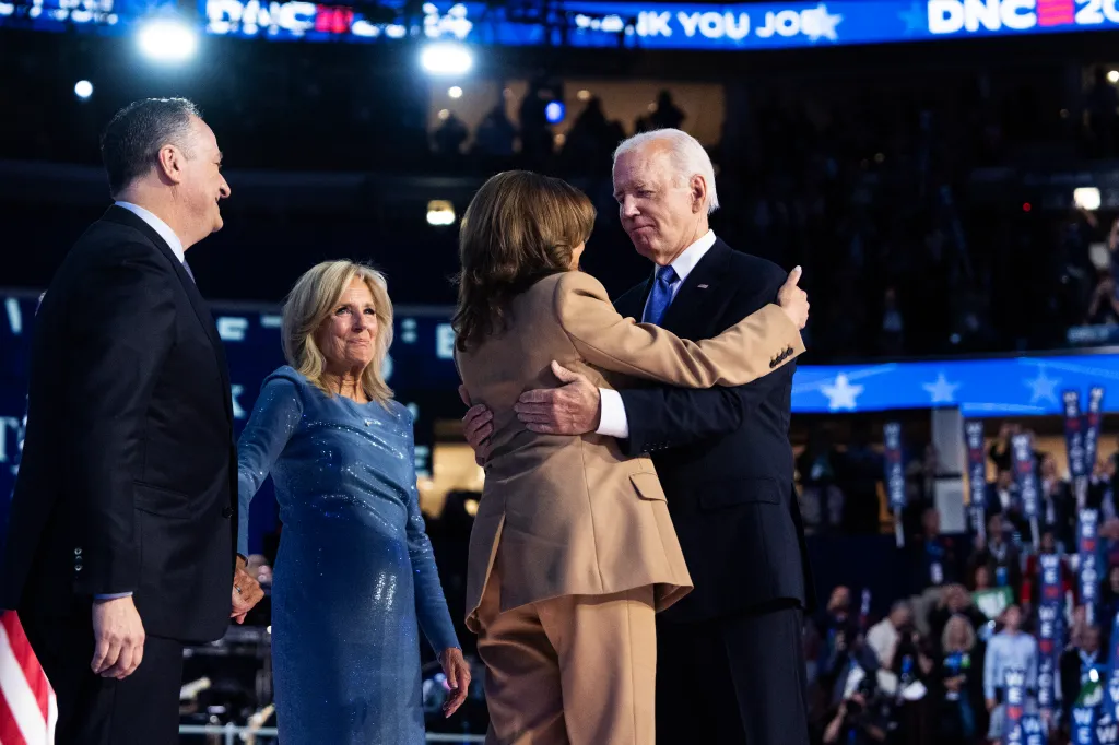 President Joe Biden and Vice President Kamala Harris embrace, with Second Gentleman Doug Emhoff and First Lady Jill Biden standing nearby, on stage at the Democratic National Convention.