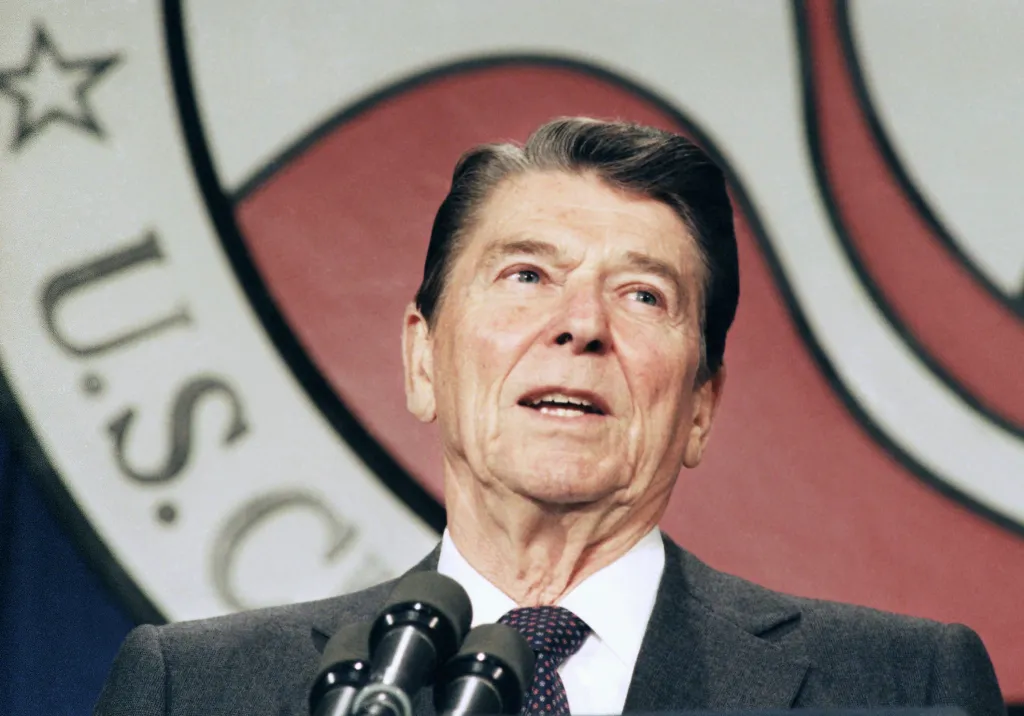 President Ronald Reagan speaks at a microphone in front of a U.S. Chamber of Commerce logo.