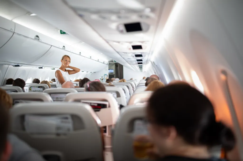 A woman stands in an airplane aisle stretching her neck.
