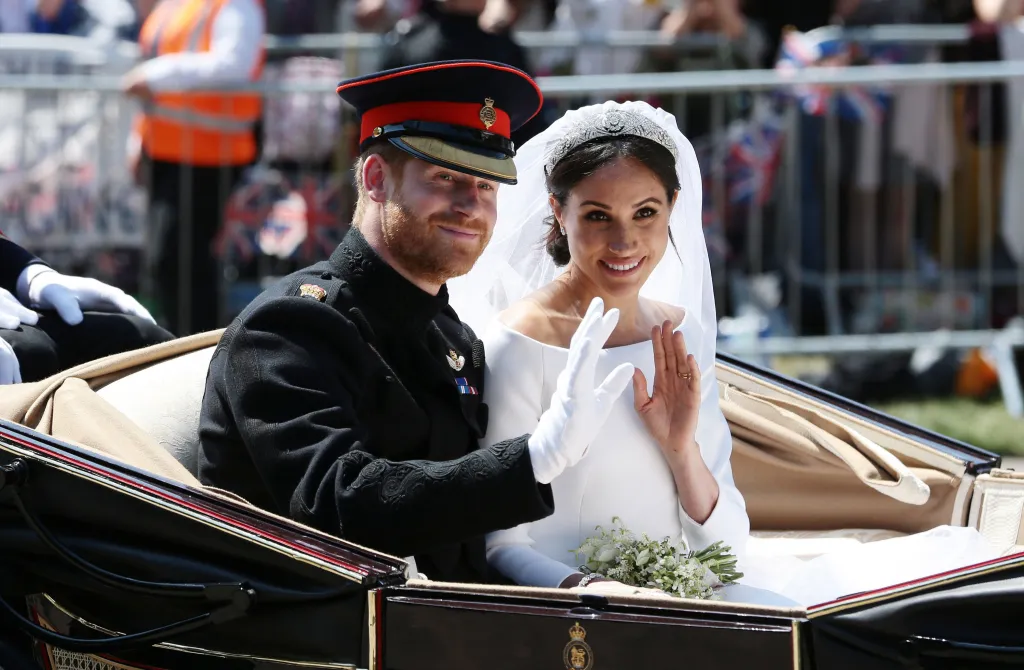 Prince Harry and Meghan Markle waving from a carriage after their wedding ceremony.