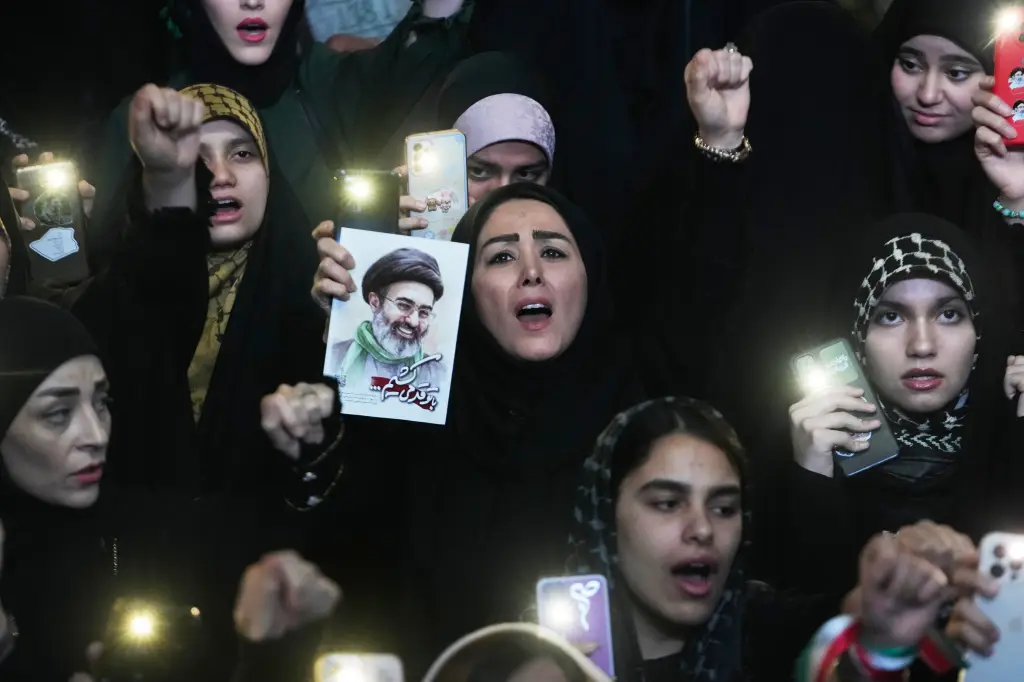 Pro-government demonstrators in Tehran, Iran, chant slogans as one holds a picture of Iranian Supreme Leader Ayatollah Mojtaba Khamenei.