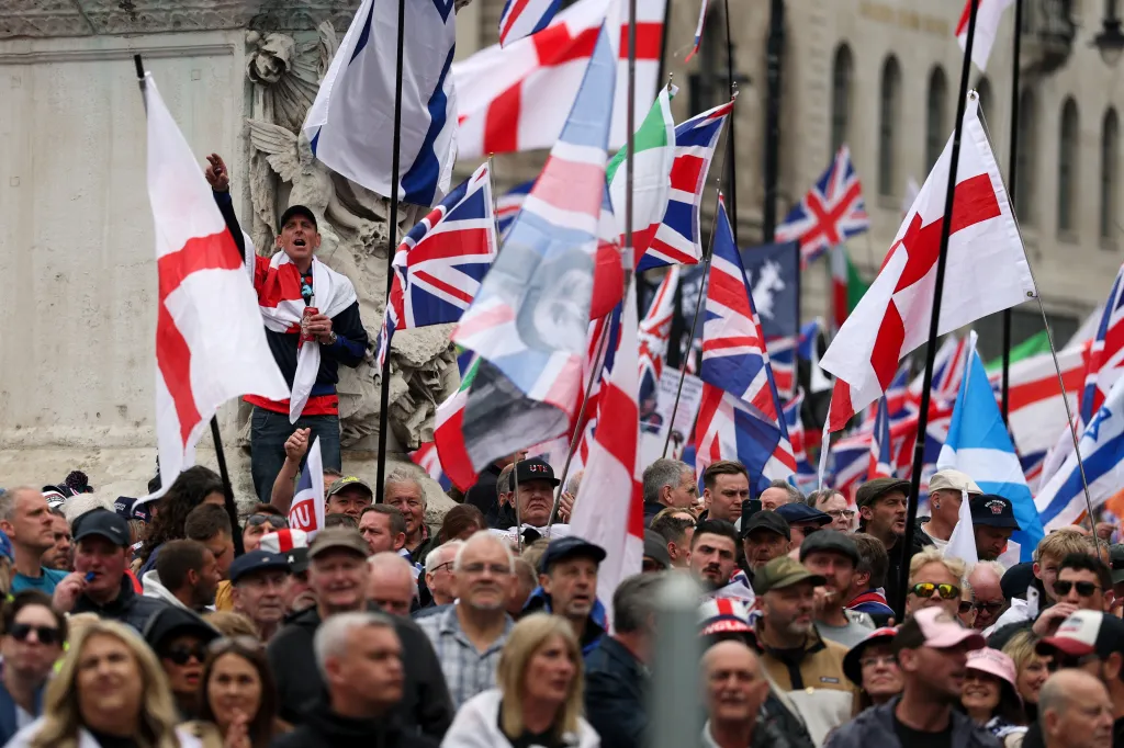 A crowd of people waving British and English flags at a 