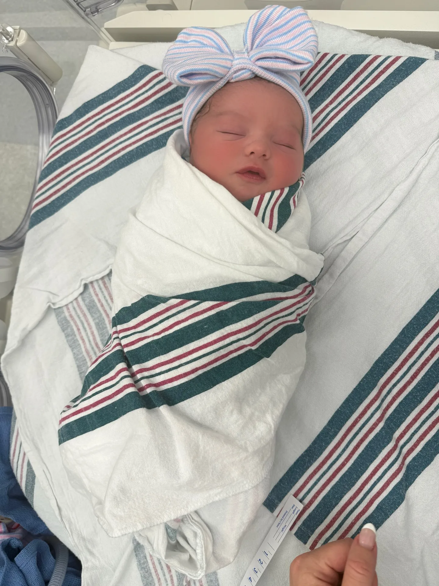 Newborn baby sleeping in a hospital blanket and hat.