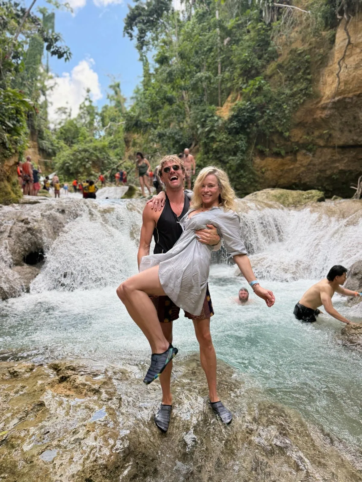 Chelsea Handler being carried by Joe Largura in a waterfall in Jamaica.