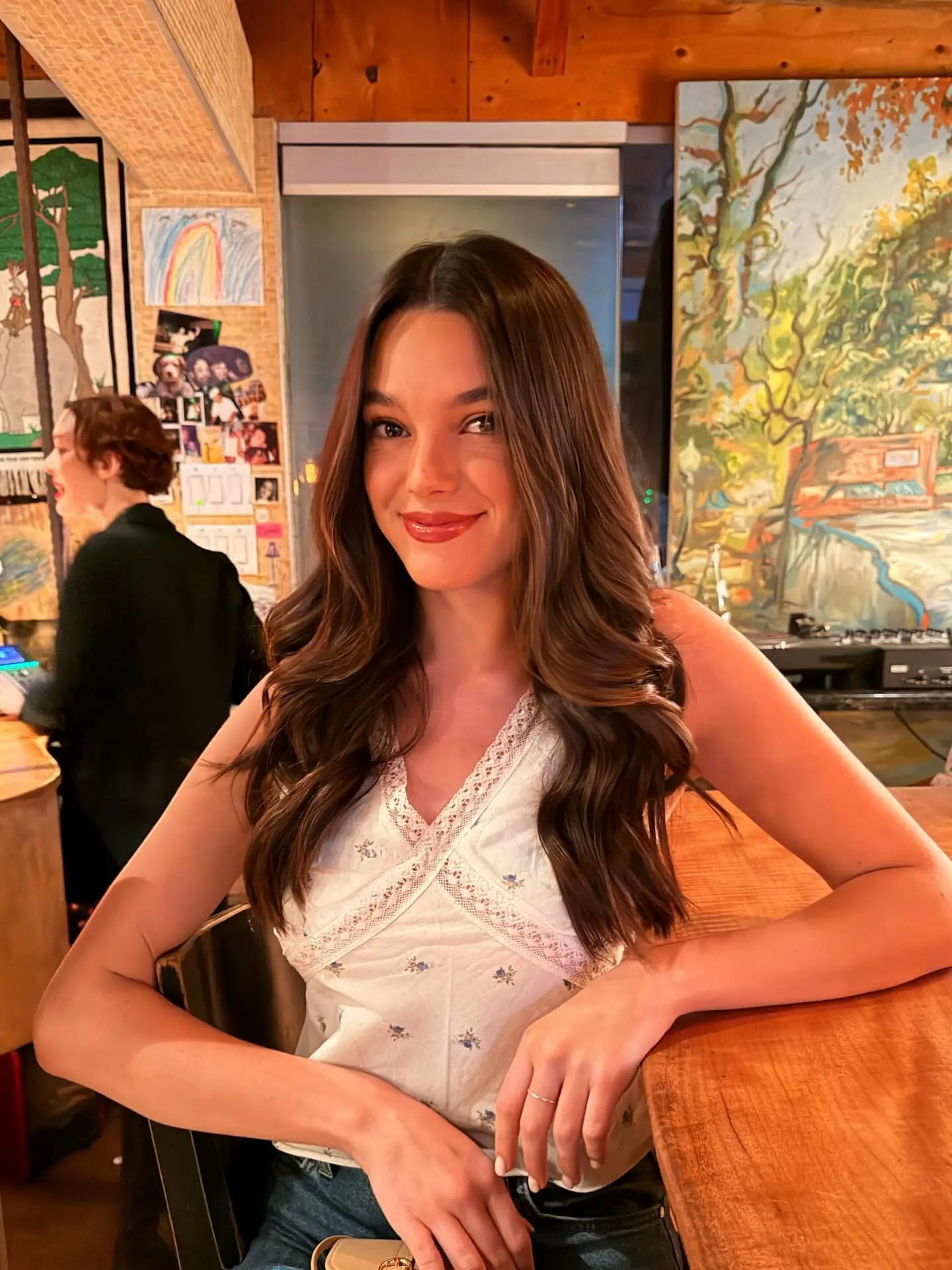 Ally Lewber smiling at a wooden table in a dimly lit space.