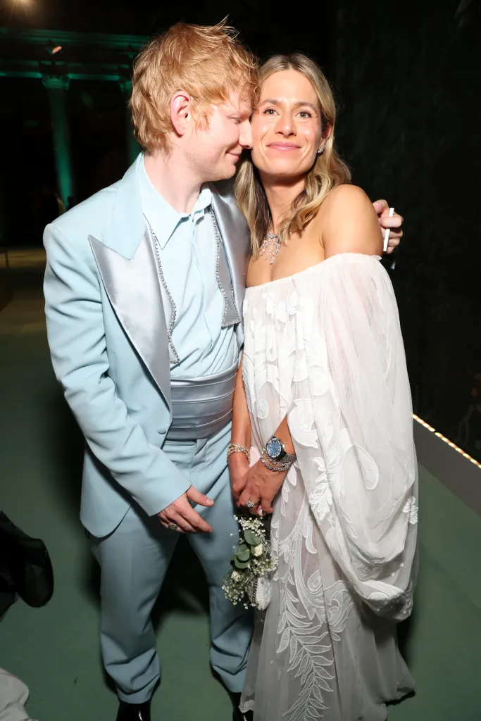 Ed Sheeran in a light blue suit and Cherry Seaborn in a white off-the-shoulder dress pose together at the 2024 Met Gala.