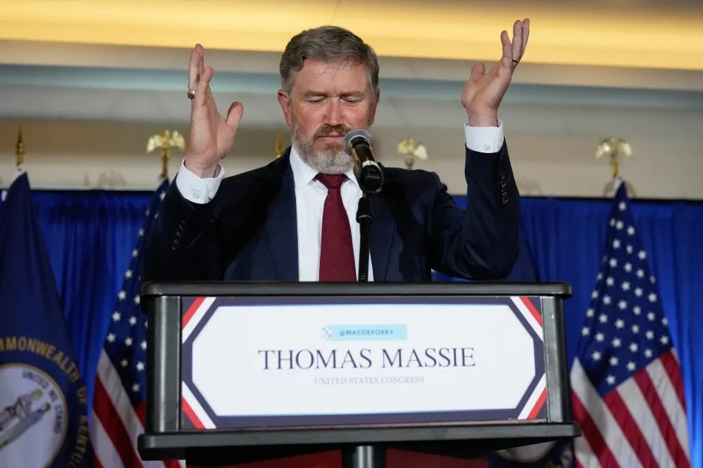 Rep. Thomas Massie gestures while speaking at a podium with a microphone.