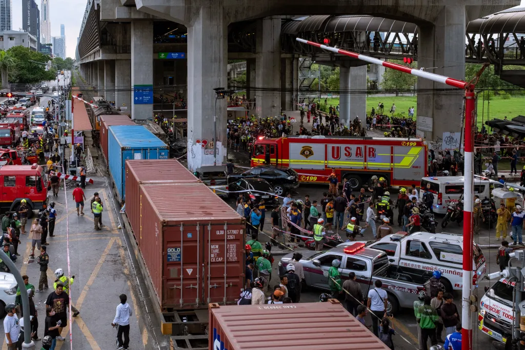 Emergency crews and onlookers at the scene of a train-bus collision under an elevated highway in Bangkok.