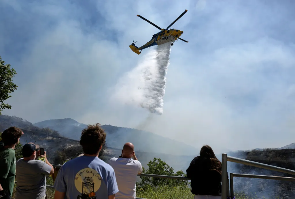Residents watch as a helicopter drops water on the Sandy Fire in Simi Valley, California.