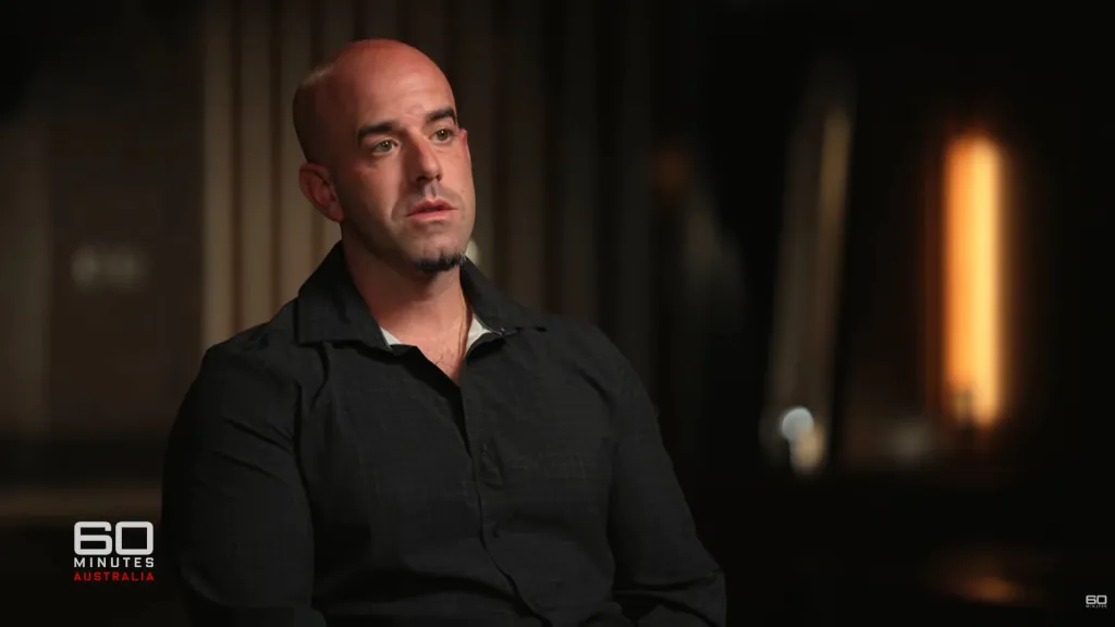 Dominic Cascio, a bald man with a short goatee, wearing a dark shirt, looking slightly to the left, during an interview with 60 Minutes Australia.
