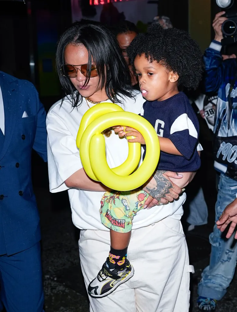 Rihanna holds her son, RZA Athelston Mayers, as he holds a yellow balloon animal.