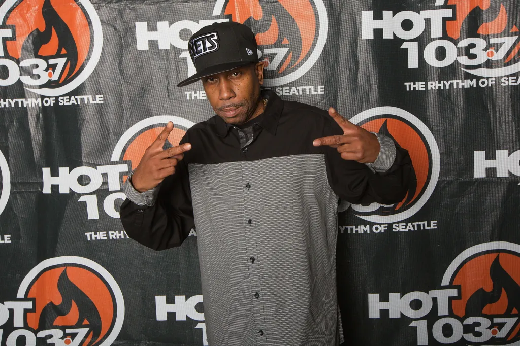 Rapper Rob Base posing for a photo in front of a Hot 103.7 FM backdrop.
