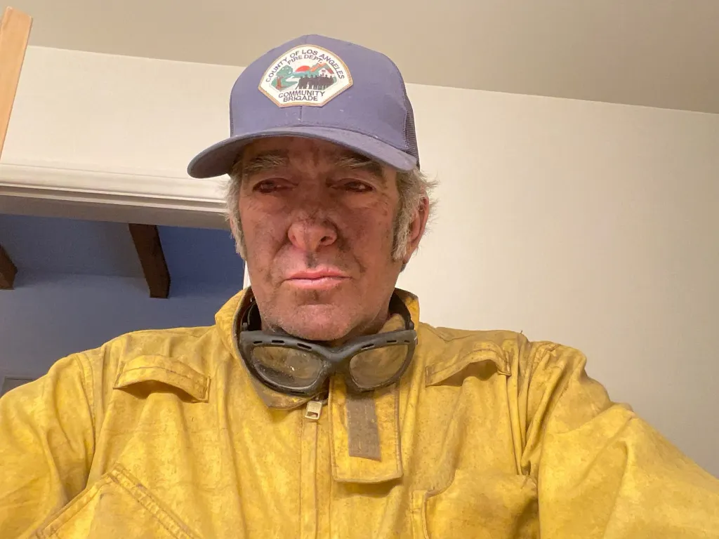 Robert Milstein, a man in a firefighter's jacket and hat, with soot on his face.