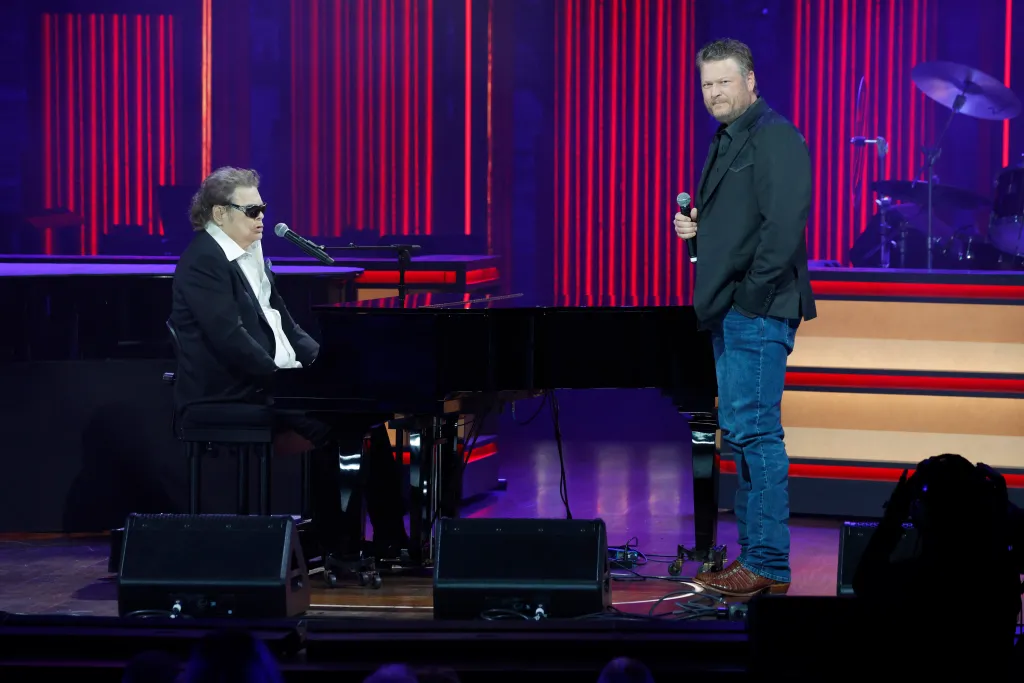 Ronnie Milsap playing piano and Blake Shelton singing onstage.