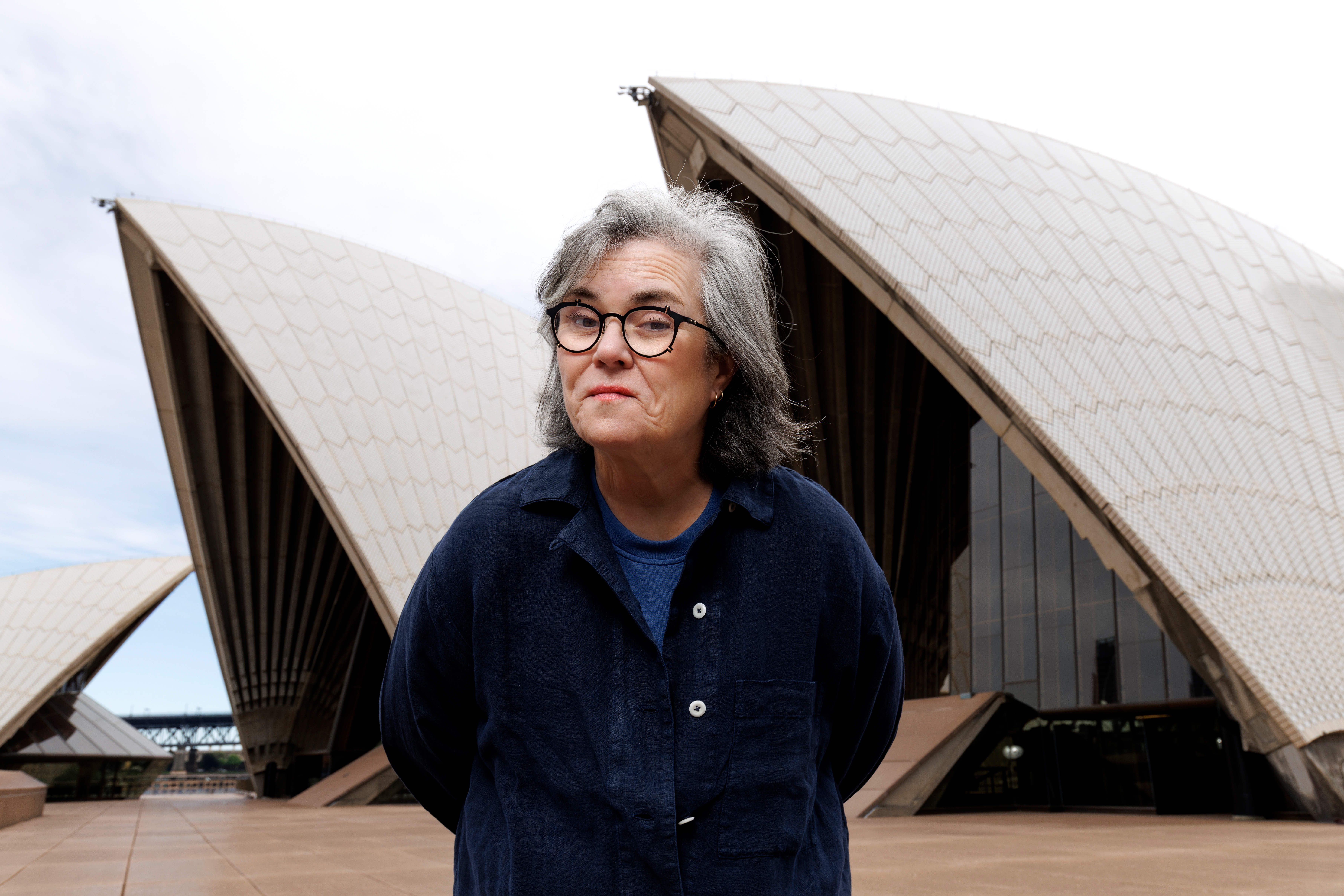 Rosie O'Donnell standing in front of the Sydney Opera House.