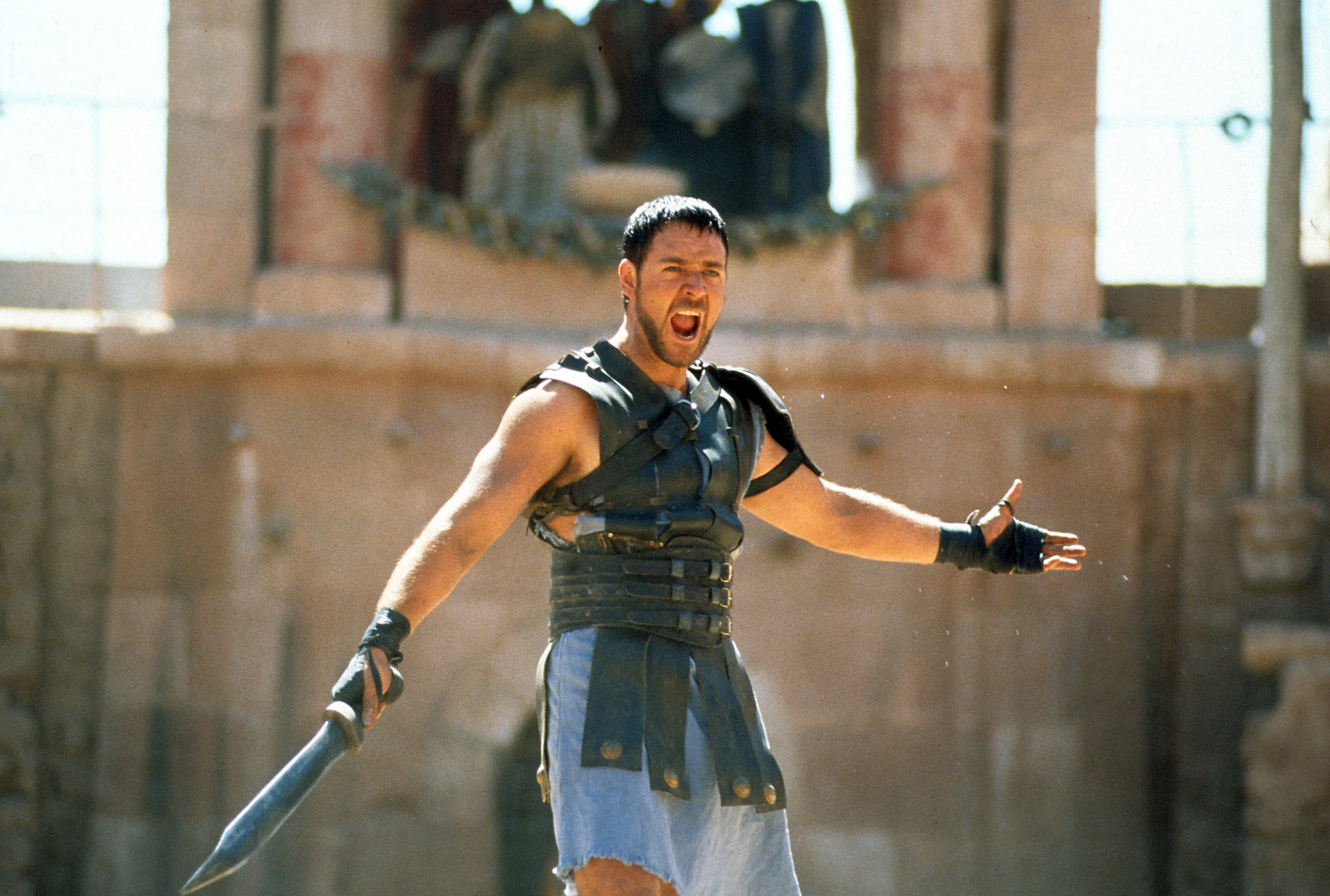 Russell Crowe as Maximus Decimus Meridius in 'Gladiator' holding a sword and yelling.