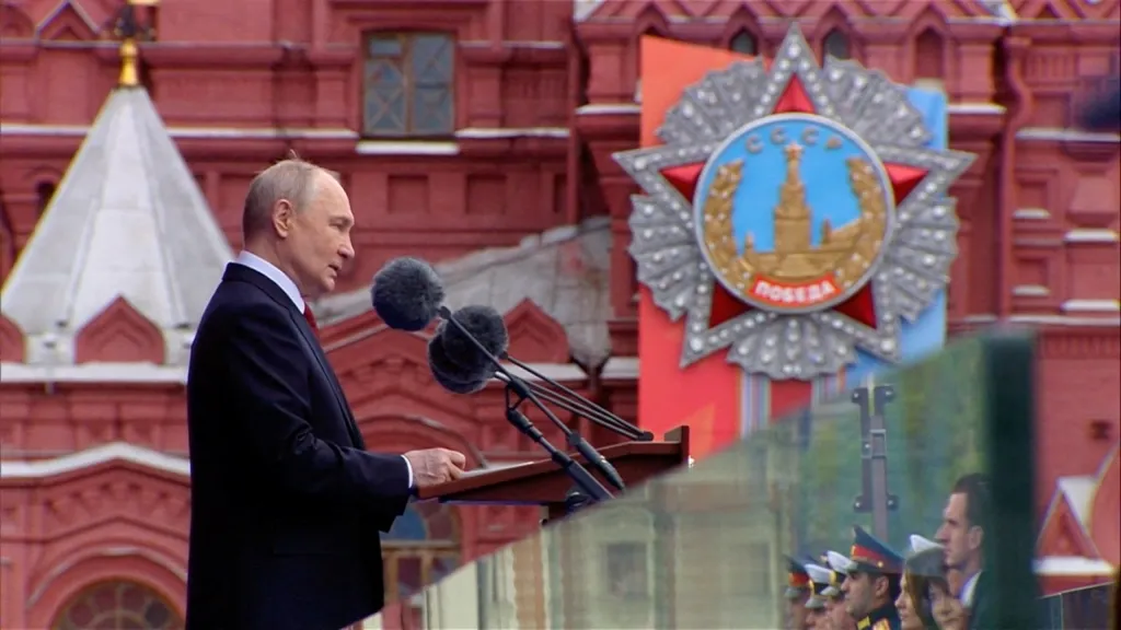 Russian President Vladimir Putin delivering a speech at a podium during a military parade in Moscow.