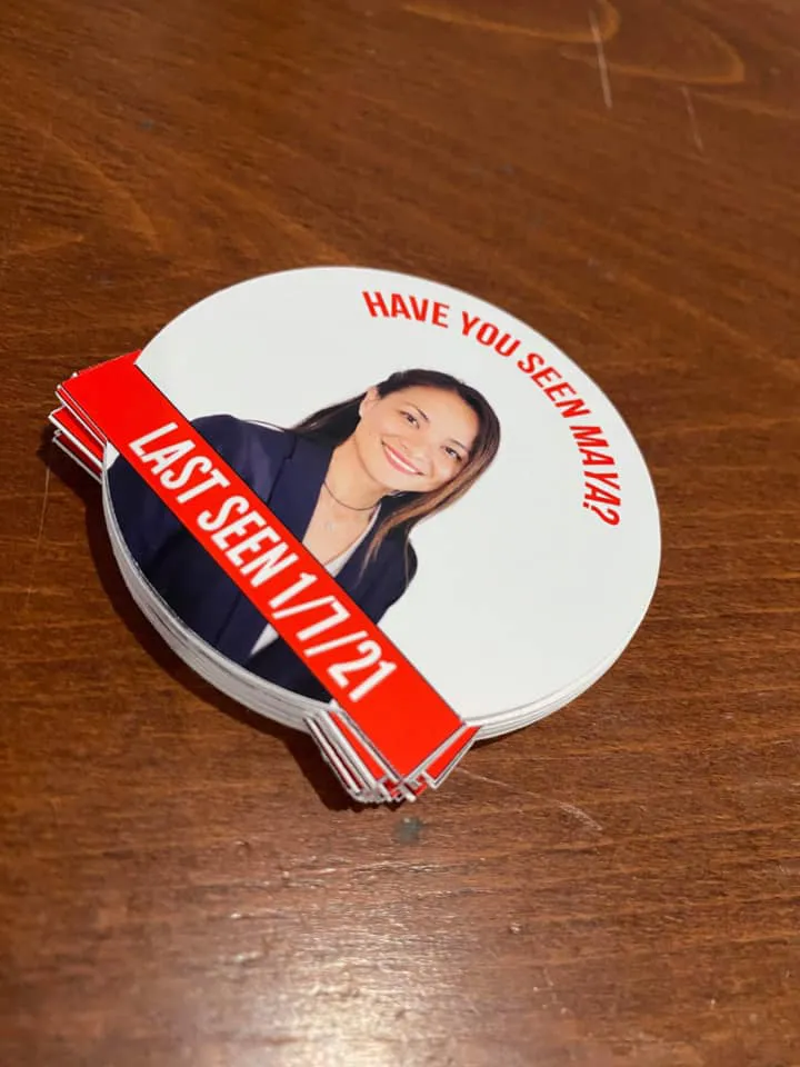 A stack of white circular stickers with a photo of Maya Millete, with the text 