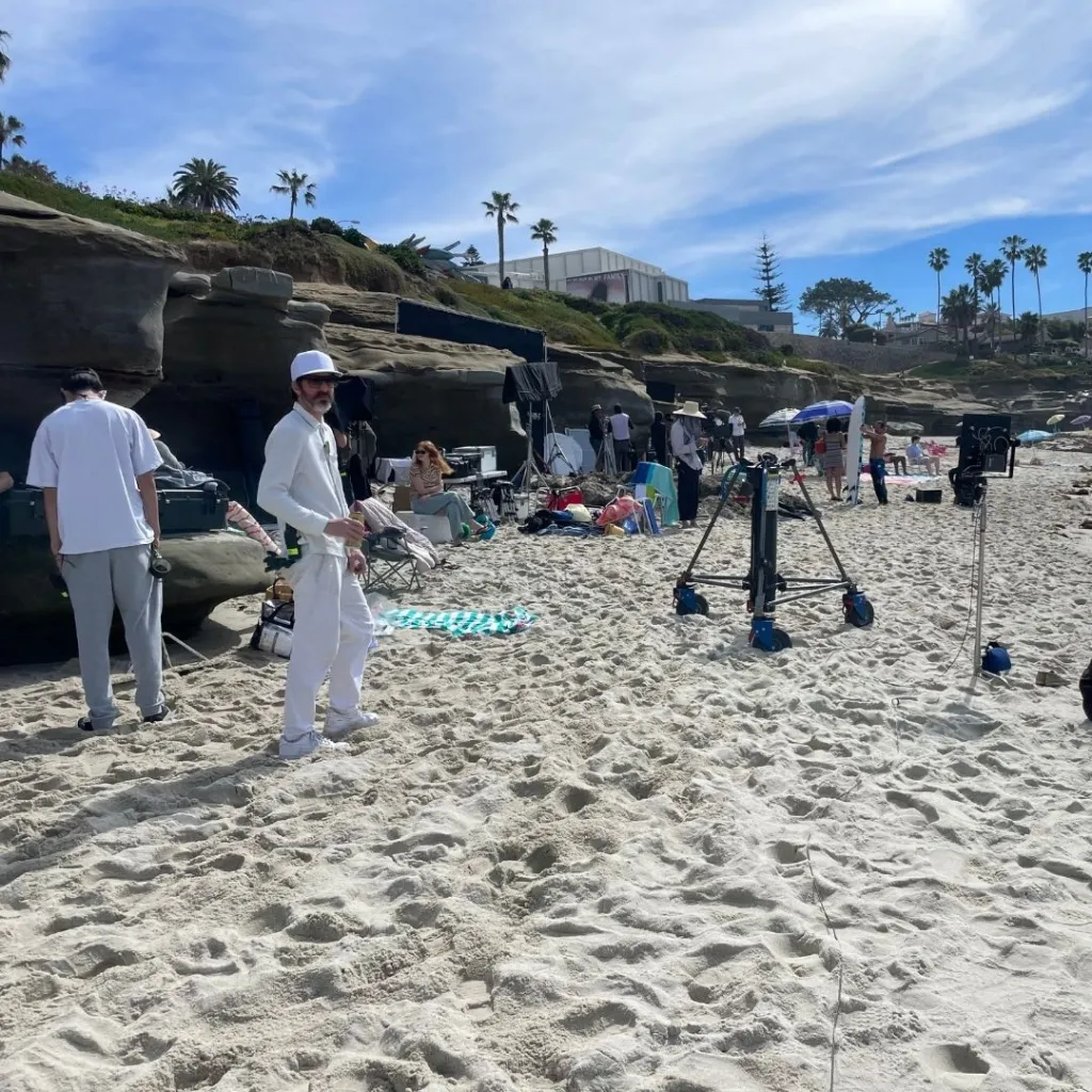 A film set on a sunny beach in San Diego with crew and equipment.