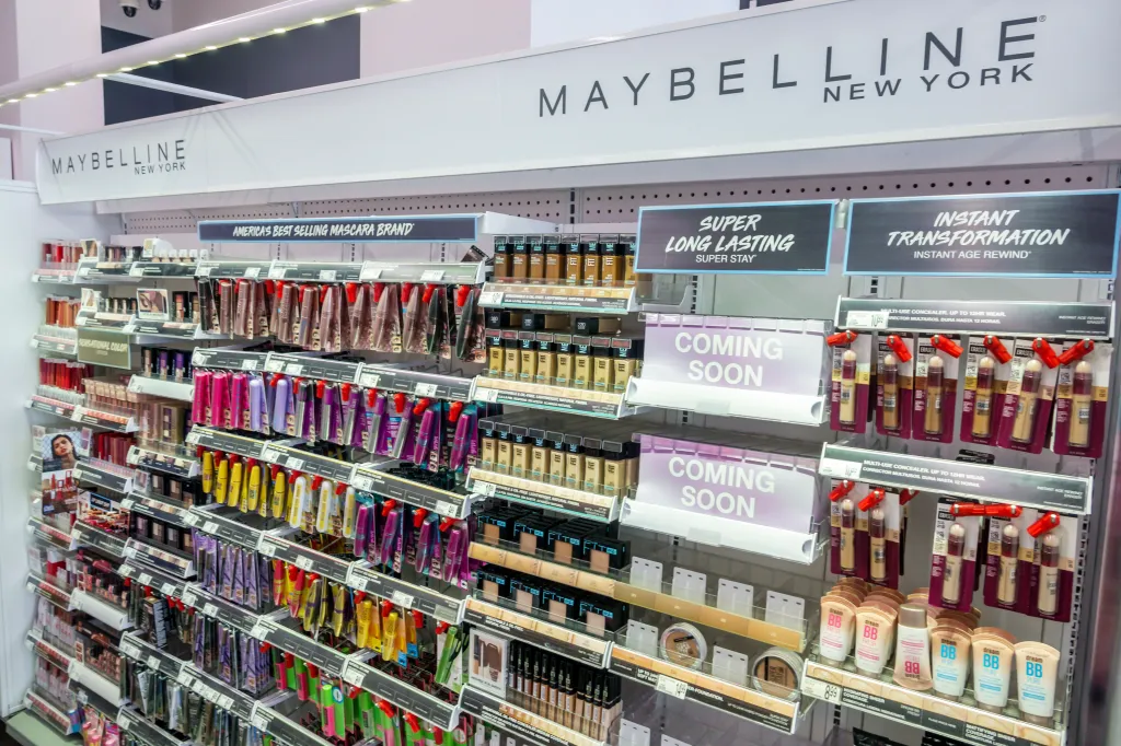 Shelves of Maybelline New York beauty products, including mascara, foundation, concealer, and BB cream, at a Walgreens pharmacy.