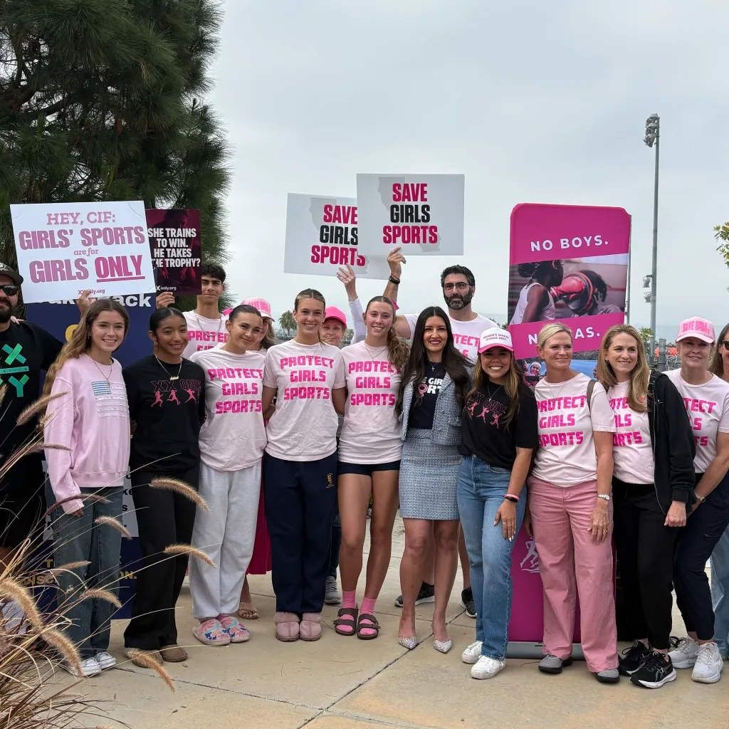 A group of women and men hold signs and wear shirts advocating for 