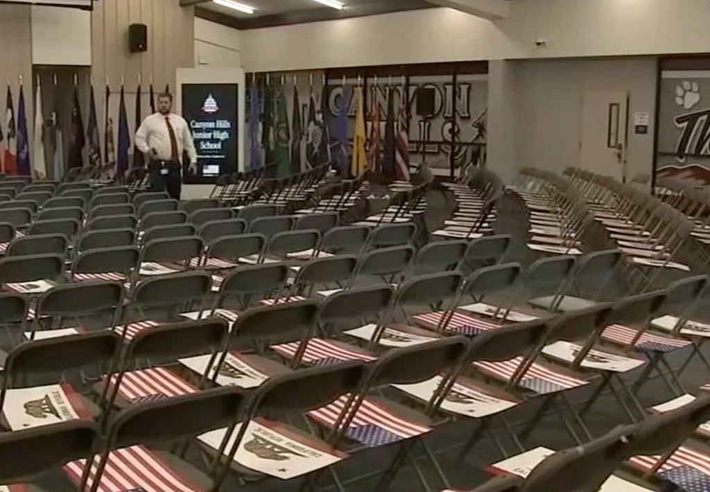 Empty chairs in an assembly room, each with a US flag on the seat and a California Republic flag on the backrest.
