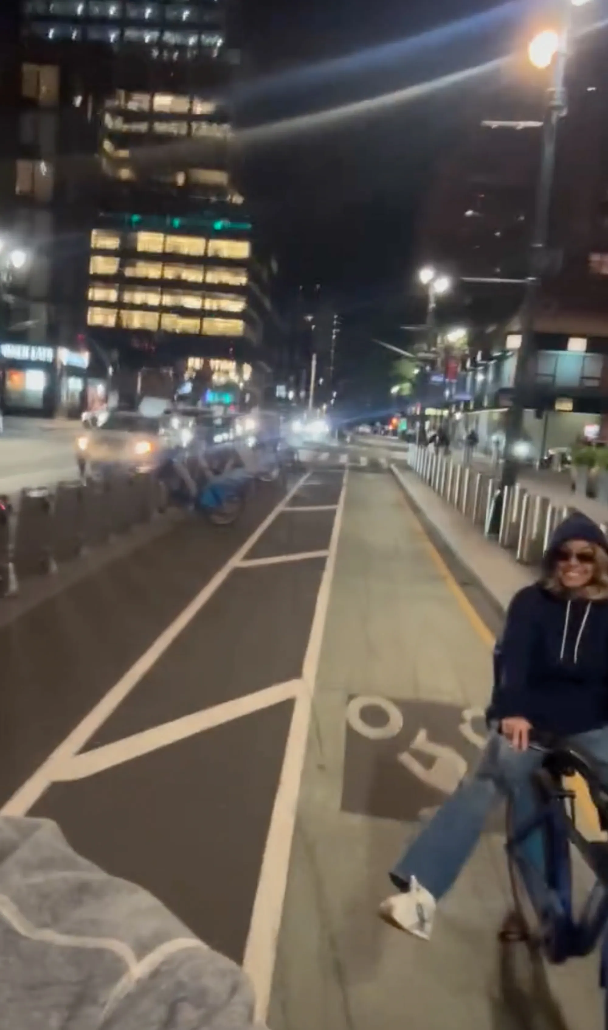 Sydney Sweeney riding a bike with Scooter Braun in Times Square at night.