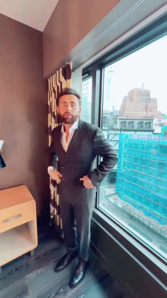 Jordan Ngatikaura in a dark suit standing by a large window.