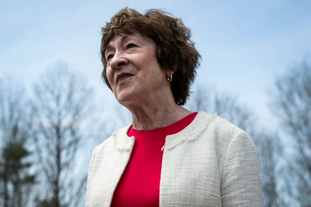 Senator Susan Collins in a red top and white jacket.