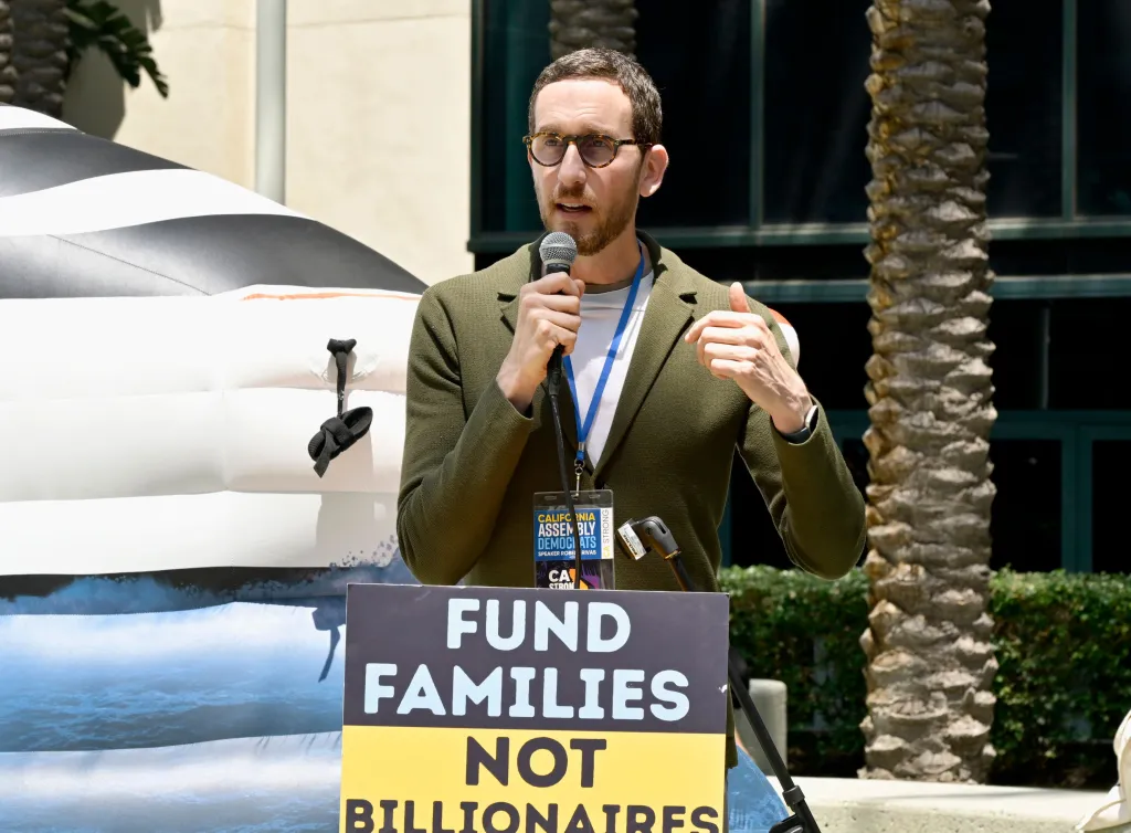 Senator Scott Wiener speaking at the CDP State Convention, with a sign that reads 