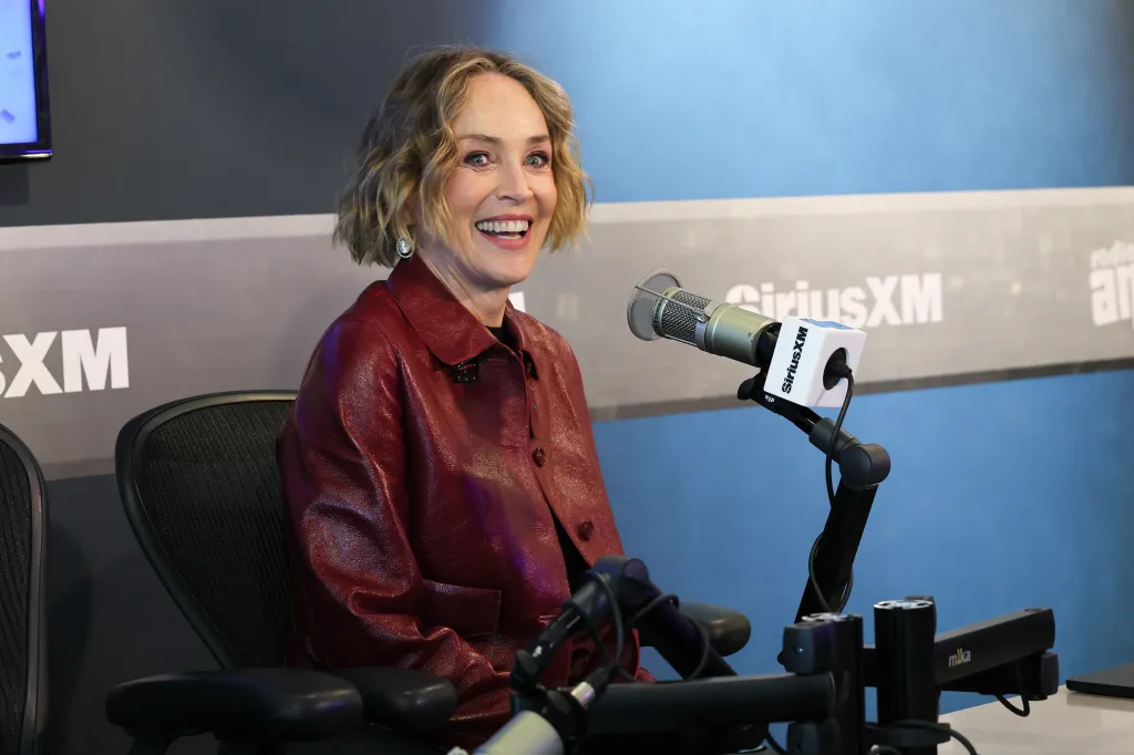 Sharon Stone in a red leather jacket, smiling at the SiriusXM studios.