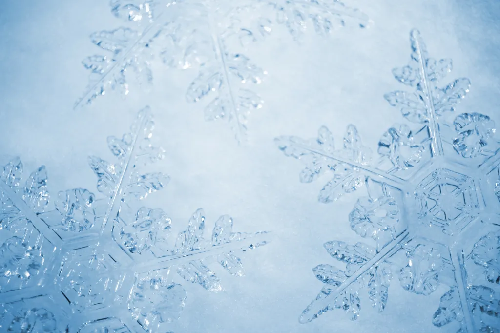 Close-up of a blue background with several translucent snowflakes.