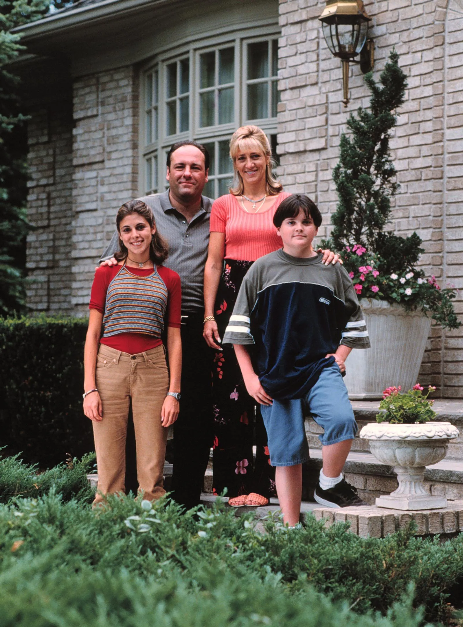 Jamie-Lynn Sigler, James Gandolfini, Edie Falco and Robert Iler posing in front of a house.