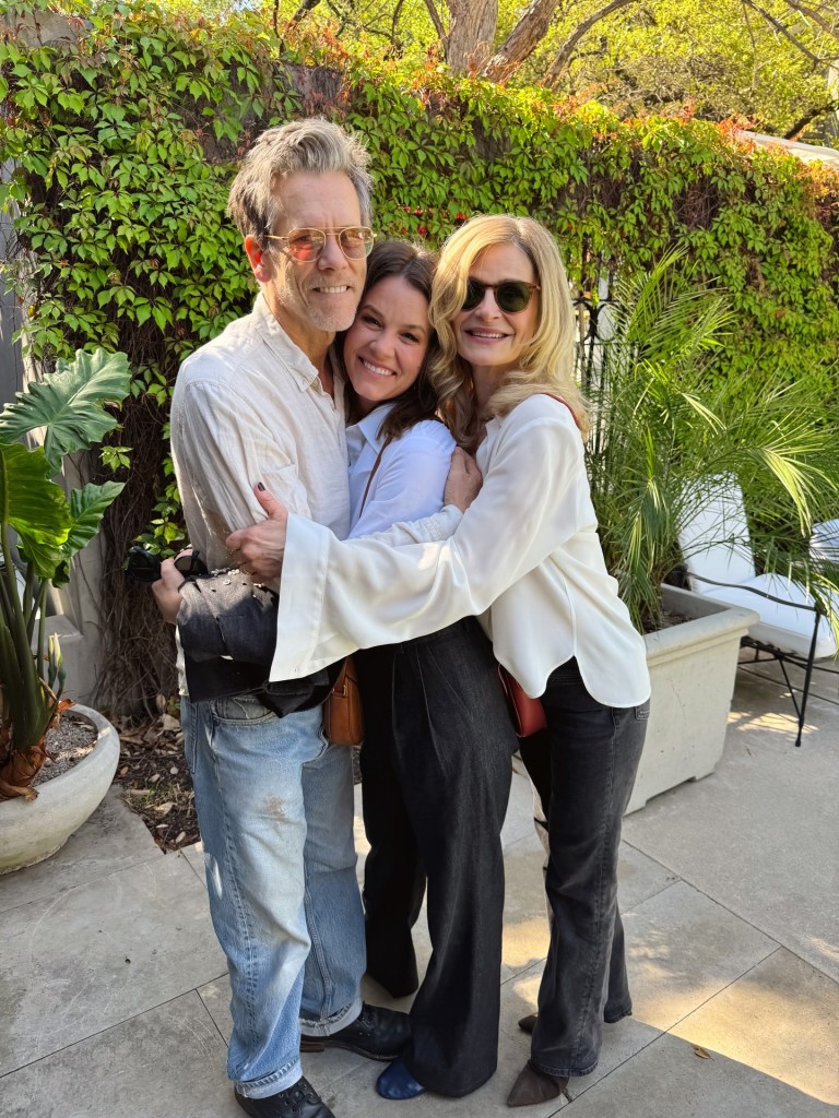 Sosie Bacon embracing Kevin Bacon and Kyra Sedgwick in an outdoor setting.