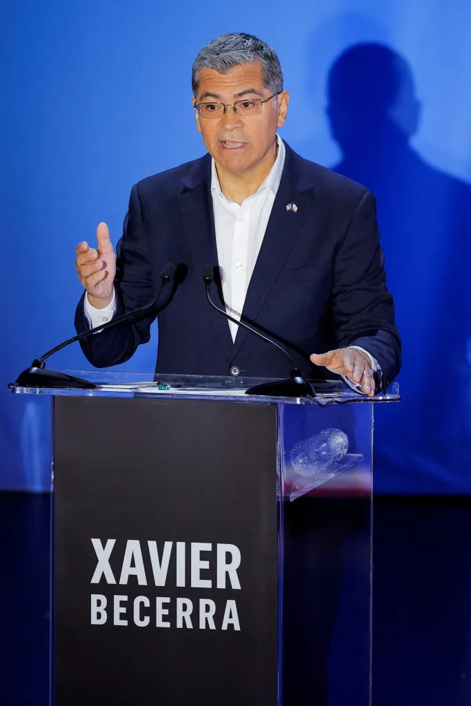 Xavier Becerra speaking at a podium with his name on it during the California gubernatorial debate.