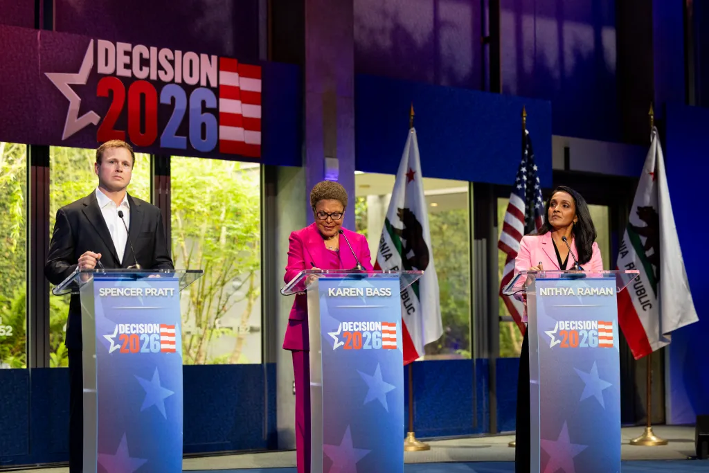 Spencer Pratt, Mayor Karen Bass, and Nithya Raman stand at podiums during a debate.