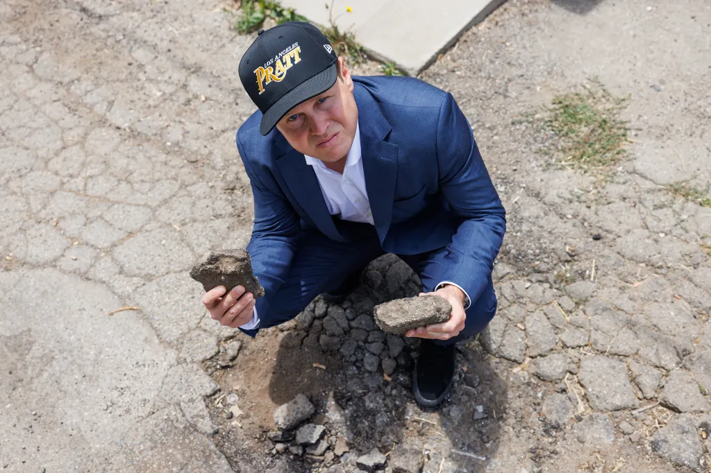 Spencer Pratt holding pieces of asphalt next to a pothole in Los Angeles.