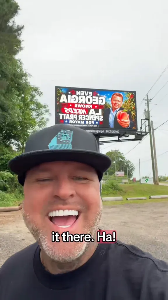 A man stands in front of a billboard that reads, 