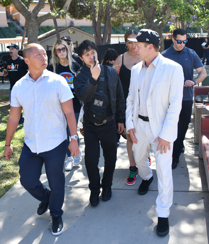 Spencer Pratt, in a white suit, with Tim Gilliam and a group of supporters in a park, meeting African American and Latino voters.