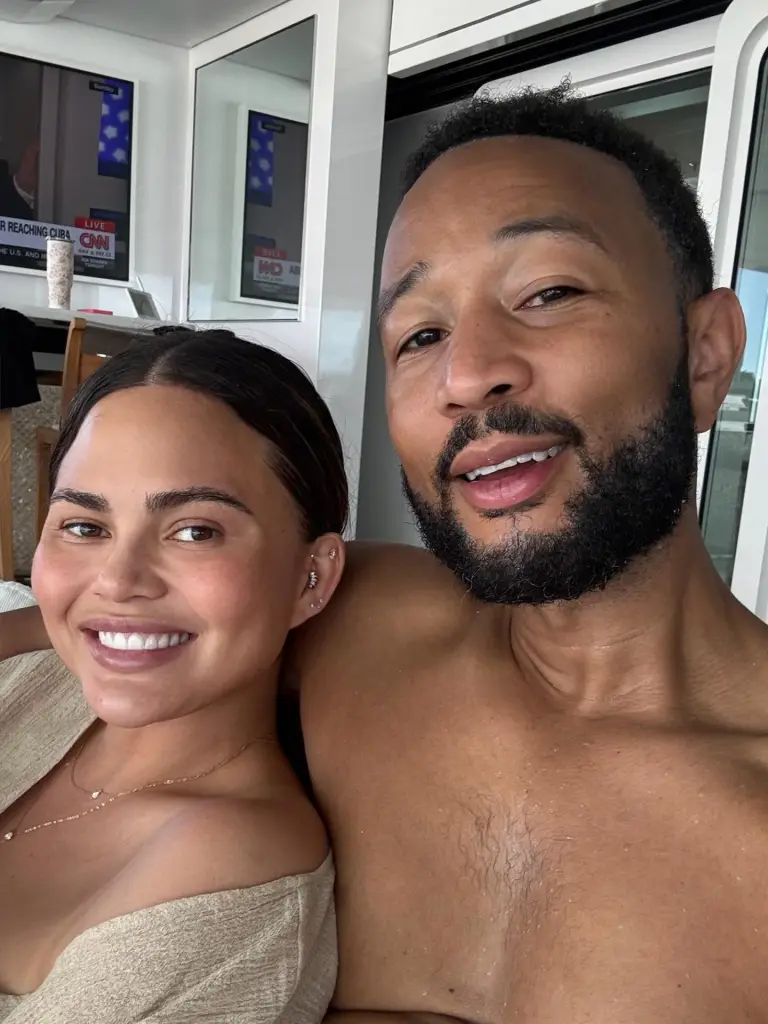 Chrissy Teigen and John Legend smiling for a selfie.